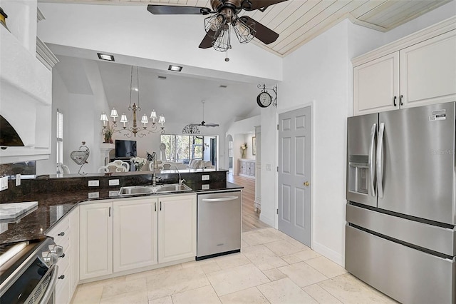 kitchen featuring lofted ceiling, a sink, stainless steel appliances, ceiling fan with notable chandelier, and open floor plan