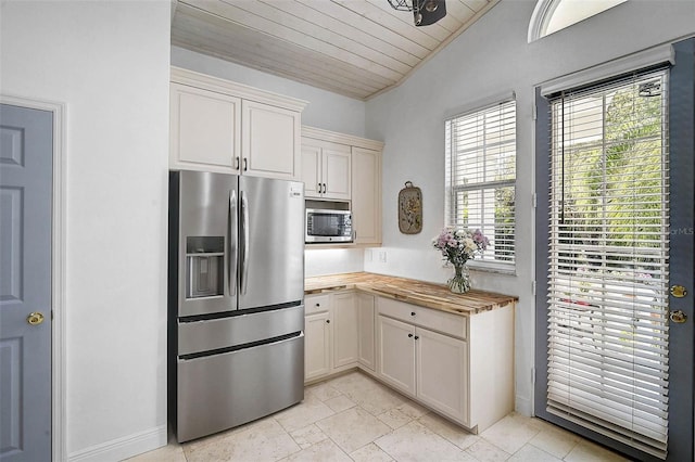 kitchen with butcher block counters, vaulted ceiling, wooden ceiling, and stainless steel appliances