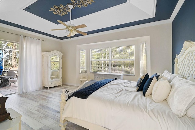 bedroom with multiple windows, a raised ceiling, and access to exterior