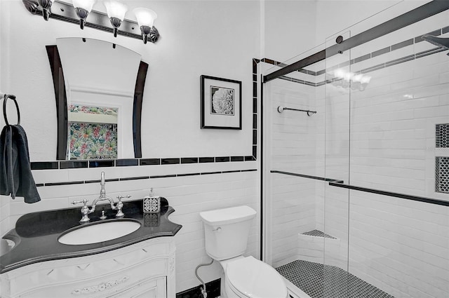 bathroom with vanity, tile walls, toilet, and a shower stall