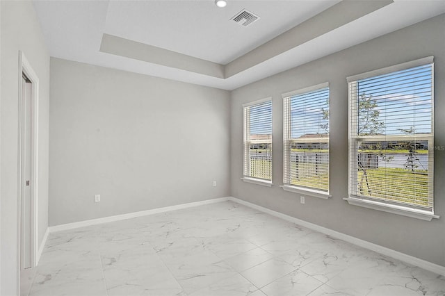 empty room featuring visible vents, baseboards, recessed lighting, marble finish floor, and a raised ceiling