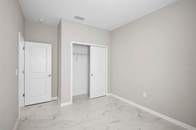 unfurnished bedroom with a closet, baseboards, visible vents, and marble finish floor