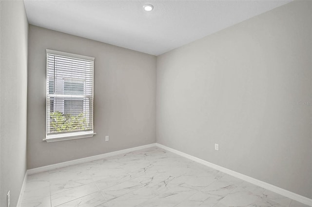 spare room with marble finish floor and baseboards