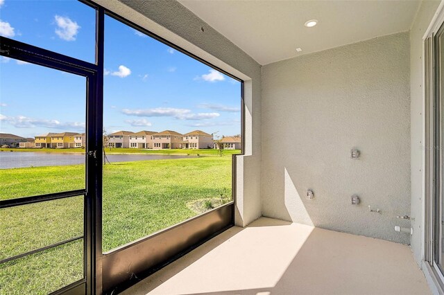 unfurnished sunroom with a wealth of natural light, a residential view, and a water view