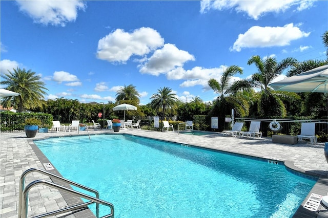 community pool with a patio area and fence