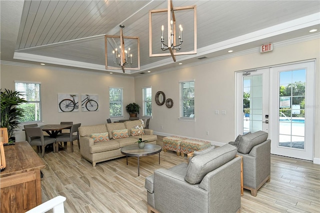 living area with light wood-style floors, a tray ceiling, a chandelier, and ornamental molding