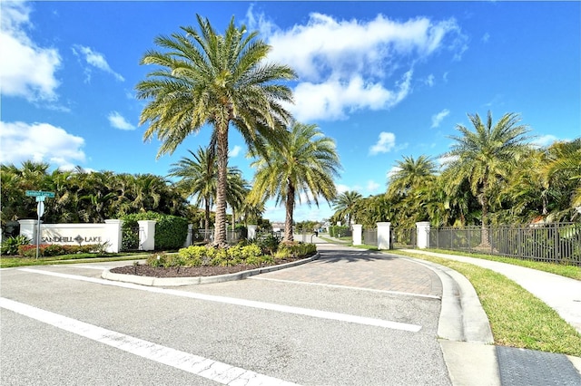 view of road featuring curbs, a gated entry, sidewalks, and a gate