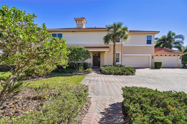 mediterranean / spanish-style house with stucco siding, a tile roof, decorative driveway, and a garage