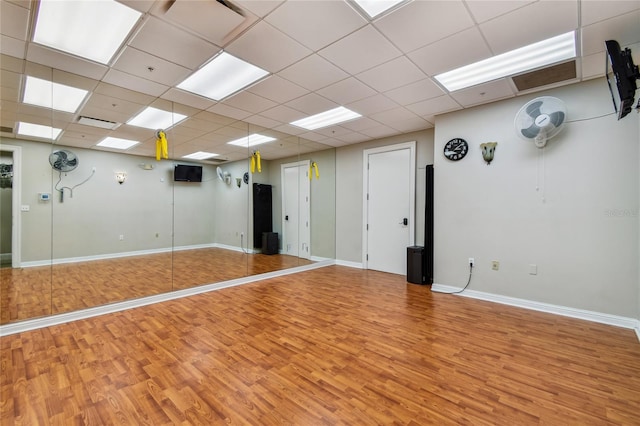 empty room with wood finished floors, baseboards, and a drop ceiling