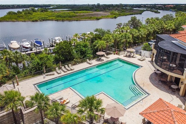 pool featuring fence, a patio, and a water view