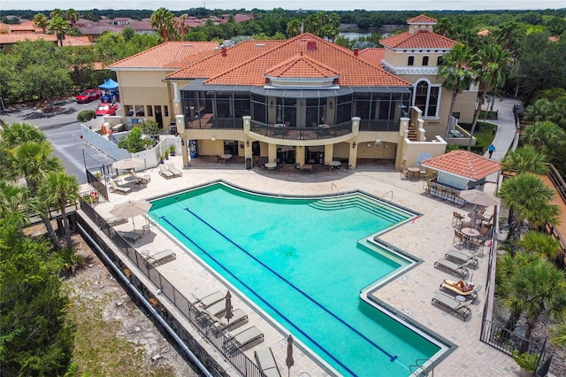 community pool with a patio area, fence, and a sunroom