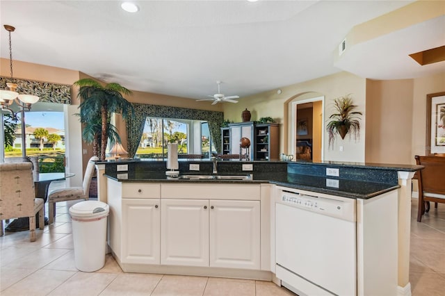 kitchen featuring plenty of natural light, dishwasher, dark stone counters, and a sink