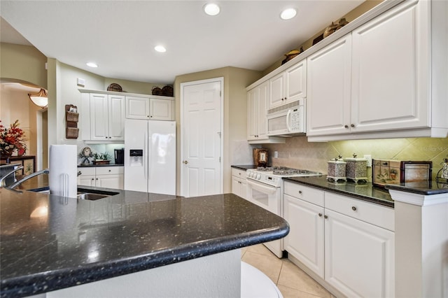 kitchen with white appliances, light tile patterned floors, a sink, decorative backsplash, and white cabinetry