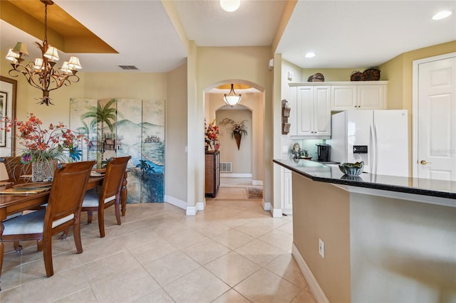 kitchen with visible vents, decorative light fixtures, white cabinetry, arched walkways, and white fridge with ice dispenser