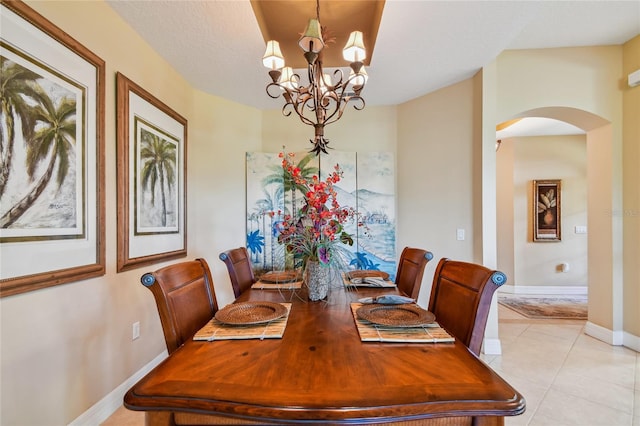 dining space with baseboards, light tile patterned floors, arched walkways, a notable chandelier, and a textured ceiling