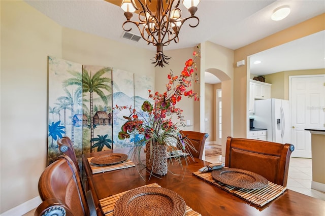 dining room with visible vents, baseboards, light tile patterned flooring, arched walkways, and a notable chandelier