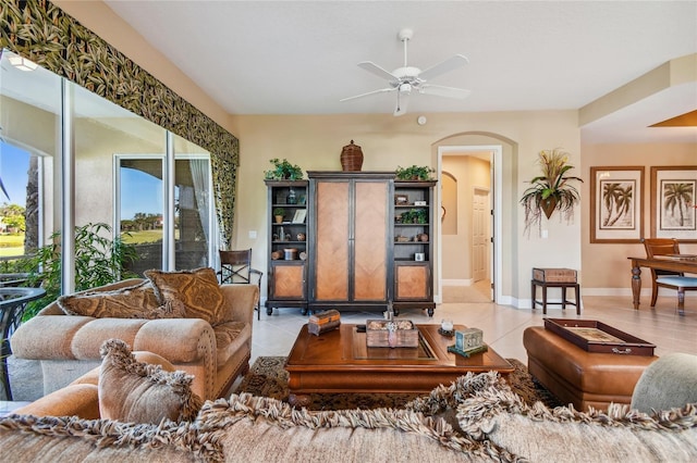 living room with baseboards, arched walkways, a ceiling fan, and tile patterned flooring