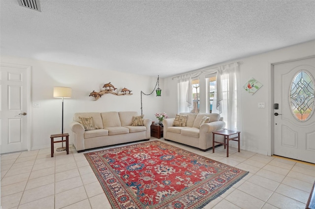 living room with visible vents, a textured ceiling, baseboards, and light tile patterned floors