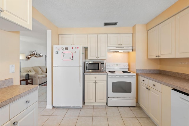 kitchen with white appliances, visible vents, a textured ceiling, under cabinet range hood, and light tile patterned flooring