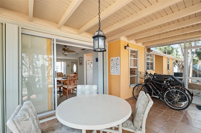 dining room featuring a ceiling fan, wood ceiling, beam ceiling, and wooden walls