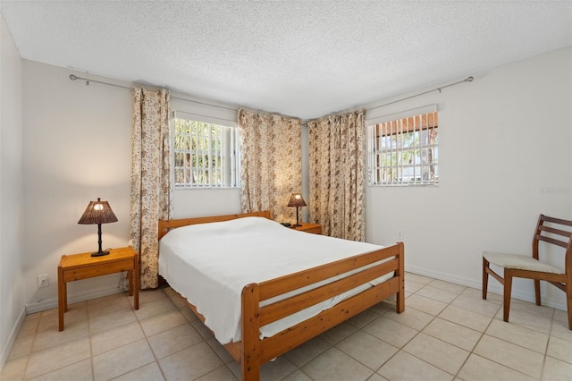 bedroom with a textured ceiling, baseboards, and light tile patterned floors