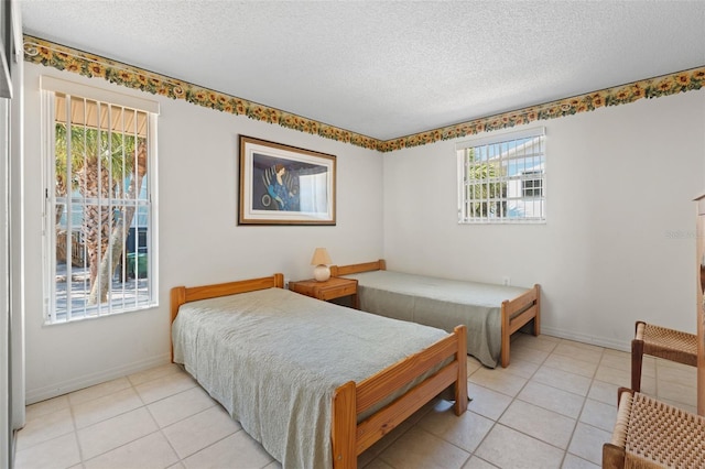 bedroom with a textured ceiling, light tile patterned floors, and baseboards