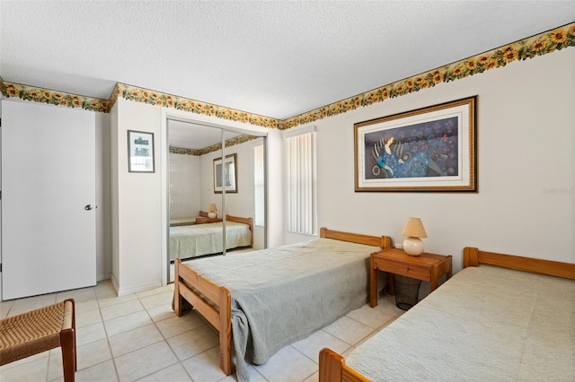 bedroom with a textured ceiling, light tile patterned floors, and a closet