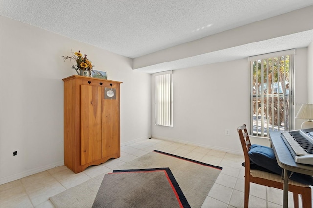 home office featuring light tile patterned floors, baseboards, and a textured ceiling