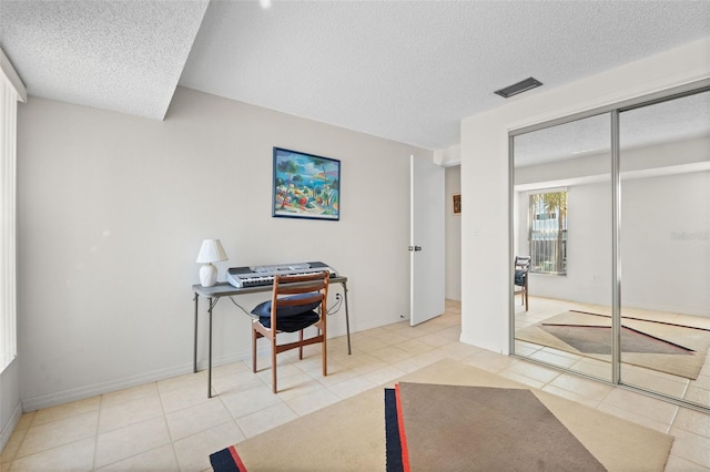 tiled home office featuring baseboards, visible vents, and a textured ceiling