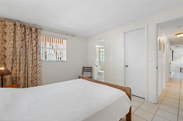 bedroom featuring light tile patterned floors, a textured ceiling, and ensuite bathroom