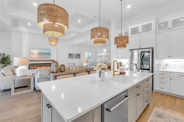 kitchen featuring open floor plan, stainless steel appliances, a sink, and a notable chandelier