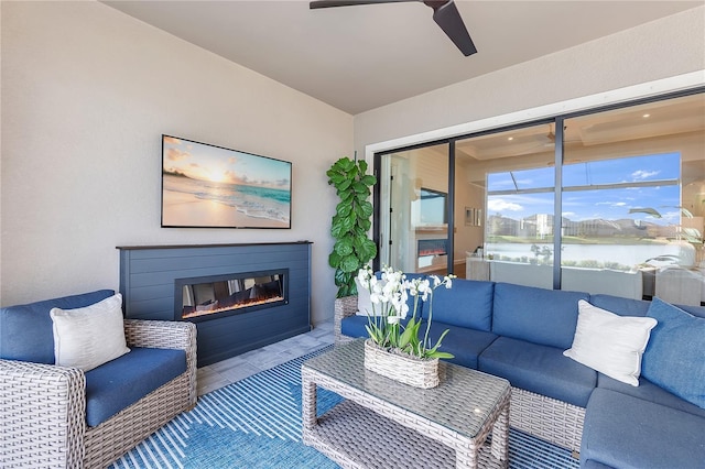 living area with a glass covered fireplace and a ceiling fan