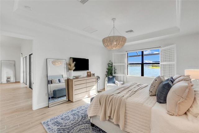 bedroom featuring a tray ceiling, visible vents, light wood-style flooring, an inviting chandelier, and baseboards