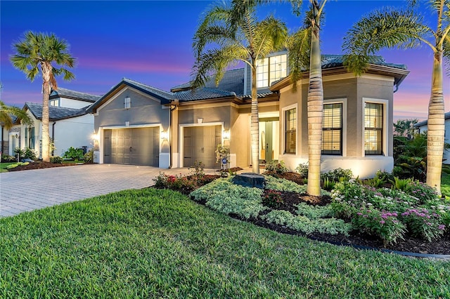 view of front of home with a garage, a yard, decorative driveway, and stucco siding