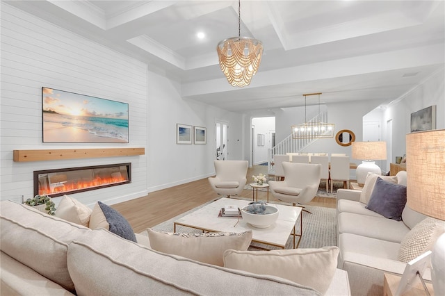 living room with stairway, an inviting chandelier, a large fireplace, wood finished floors, and coffered ceiling