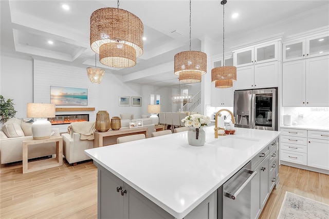 kitchen with stainless steel appliances, gray cabinetry, open floor plan, a sink, and a chandelier