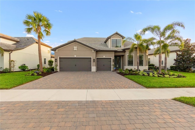 view of front of house featuring a garage, a tile roof, decorative driveway, stucco siding, and a front lawn