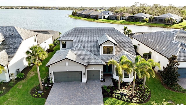 view of front of property with a water view, a tile roof, a residential view, and decorative driveway