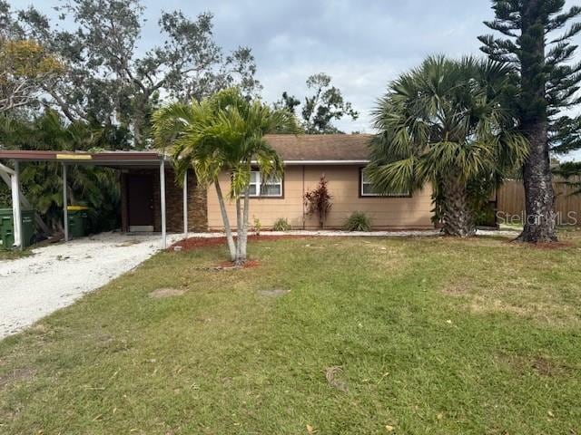 ranch-style home featuring driveway, fence, an attached carport, and a front yard