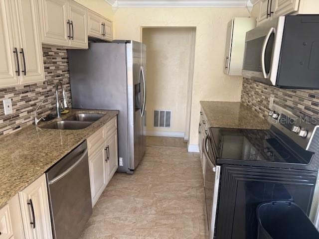 kitchen with tasteful backsplash, visible vents, ornamental molding, stainless steel appliances, and a sink