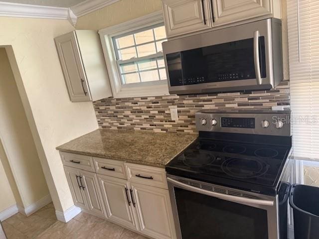 kitchen featuring crown molding, stainless steel appliances, decorative backsplash, dark stone counters, and baseboards