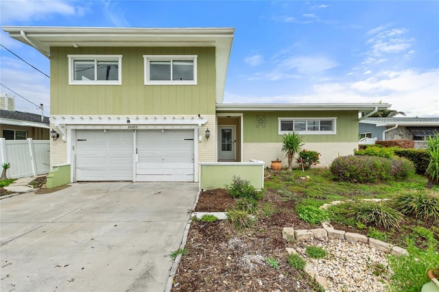 view of front of home with driveway, brick siding, an attached garage, and fence