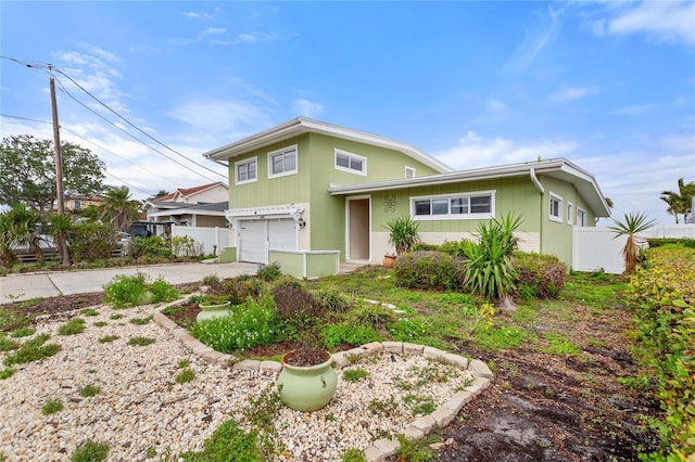 view of front of home featuring an attached garage, fence, and concrete driveway