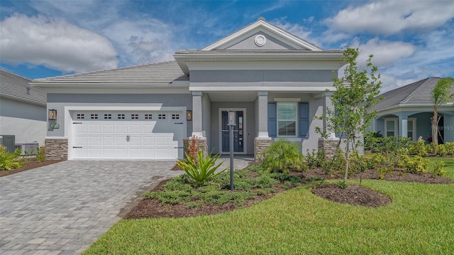 view of front of property with stone siding, decorative driveway, an attached garage, and stucco siding