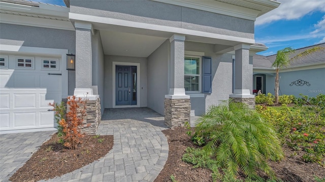 view of exterior entry featuring an attached garage, stone siding, and stucco siding