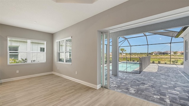 entryway with a sunroom, a textured ceiling, baseboards, and wood finished floors