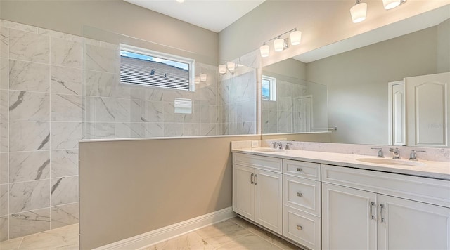 bathroom with double vanity, marble finish floor, a walk in shower, and a sink