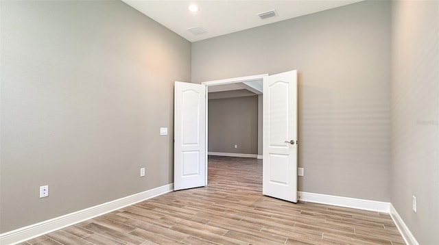 unfurnished room featuring wood finish floors, visible vents, and baseboards