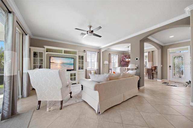 living room featuring ceiling fan with notable chandelier, arched walkways, ornamental molding, and light tile patterned flooring