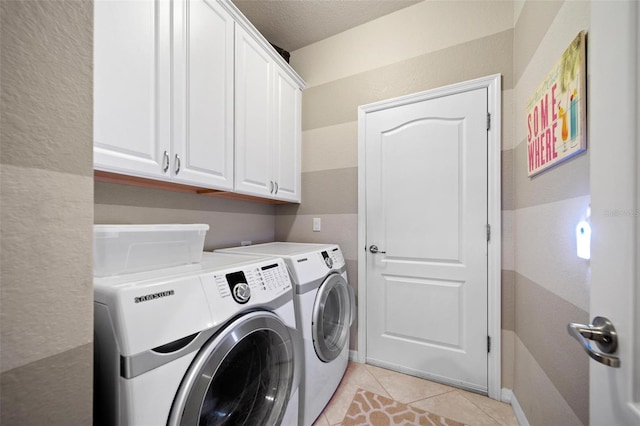 laundry area featuring cabinet space, washing machine and dryer, light tile patterned floors, and a textured ceiling